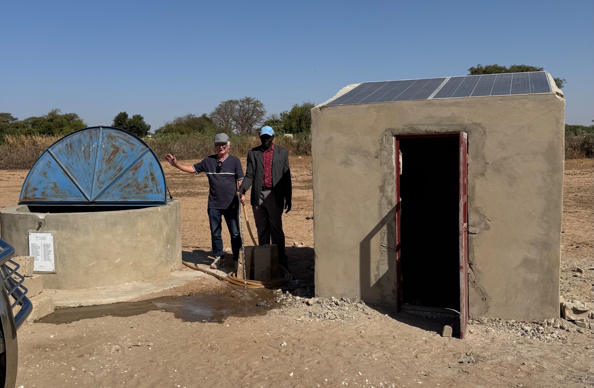 Gerätehaus mit 2 Solarpanels auf dem Dach, links daneben der abschließbare Brunnen